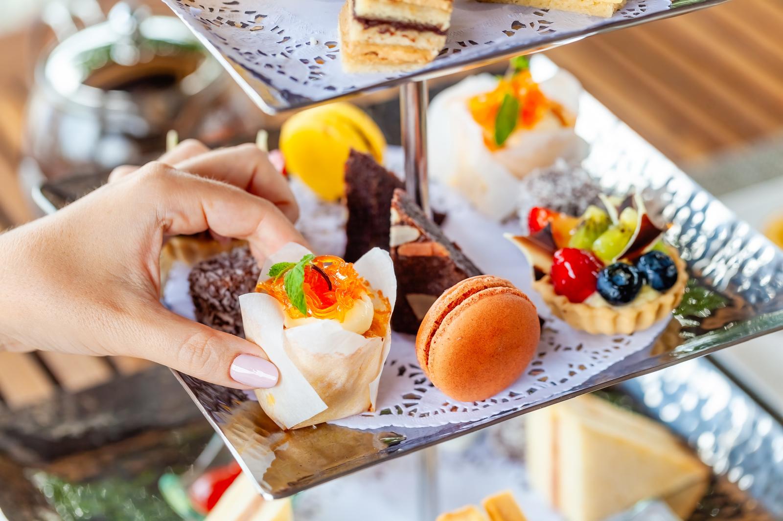 elegant high tea setup with tiered cake stands, fine china, and pastries, bright natural lighting